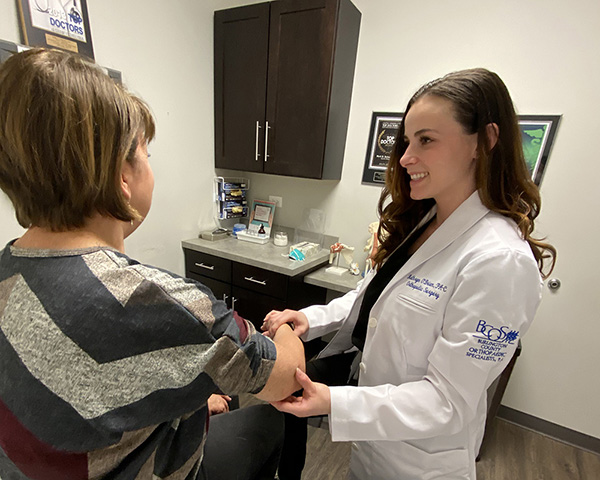 Kathryn O'Brien, PA-C examining a patient's hand in clinic