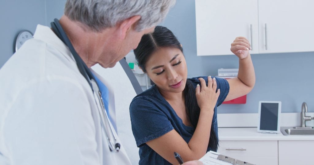 Woman explaining rotator cuff shoulder pain to doctor